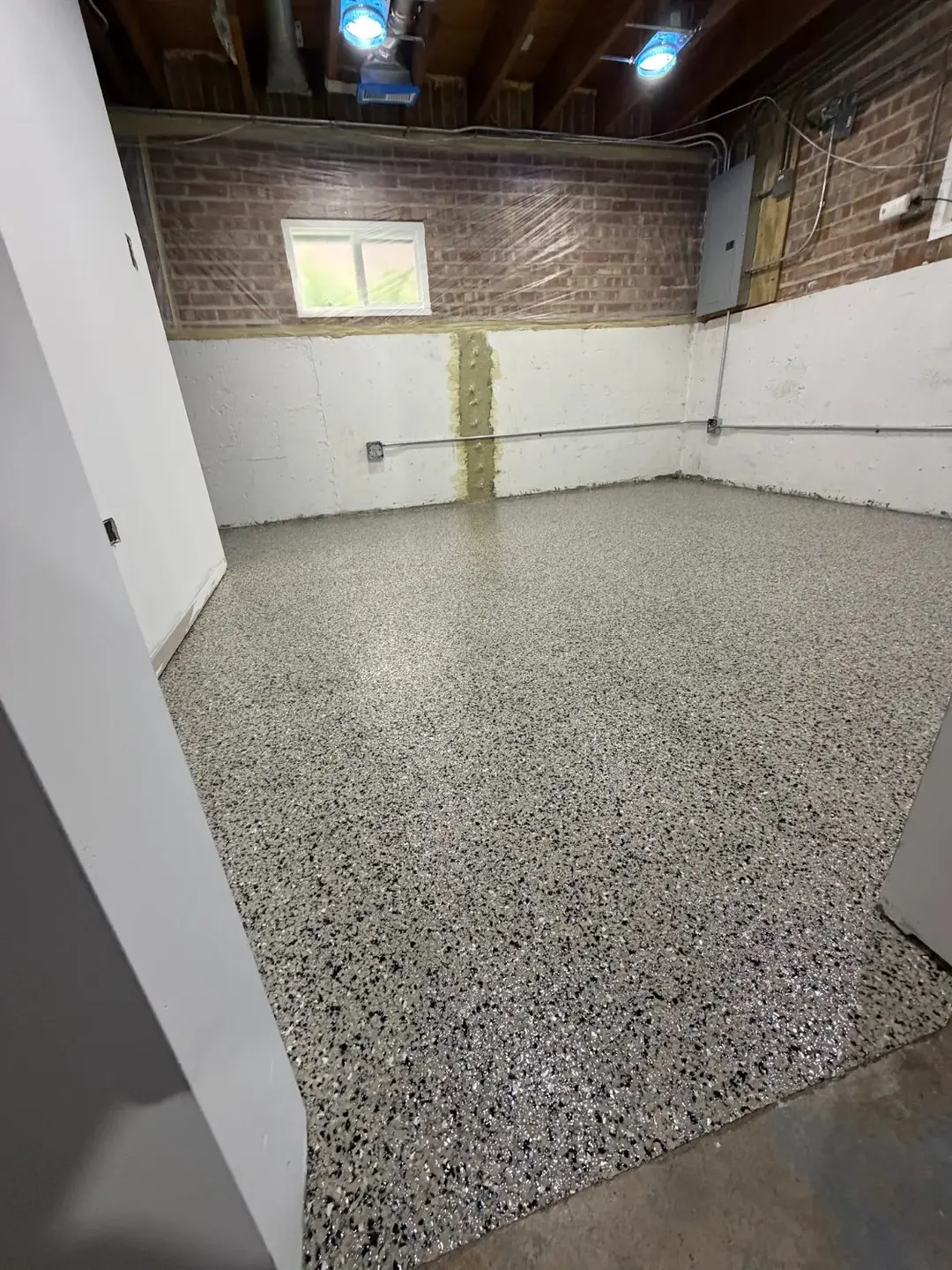 Installer spreading polyaspartic flooring coating in a Cook County - IL garage before the surface cures