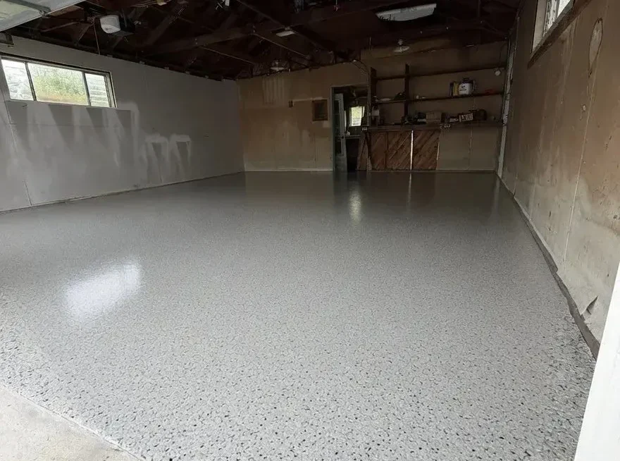 Installer spreading polyaspartic flooring coating in a Cook County - IL garage before the surface cures